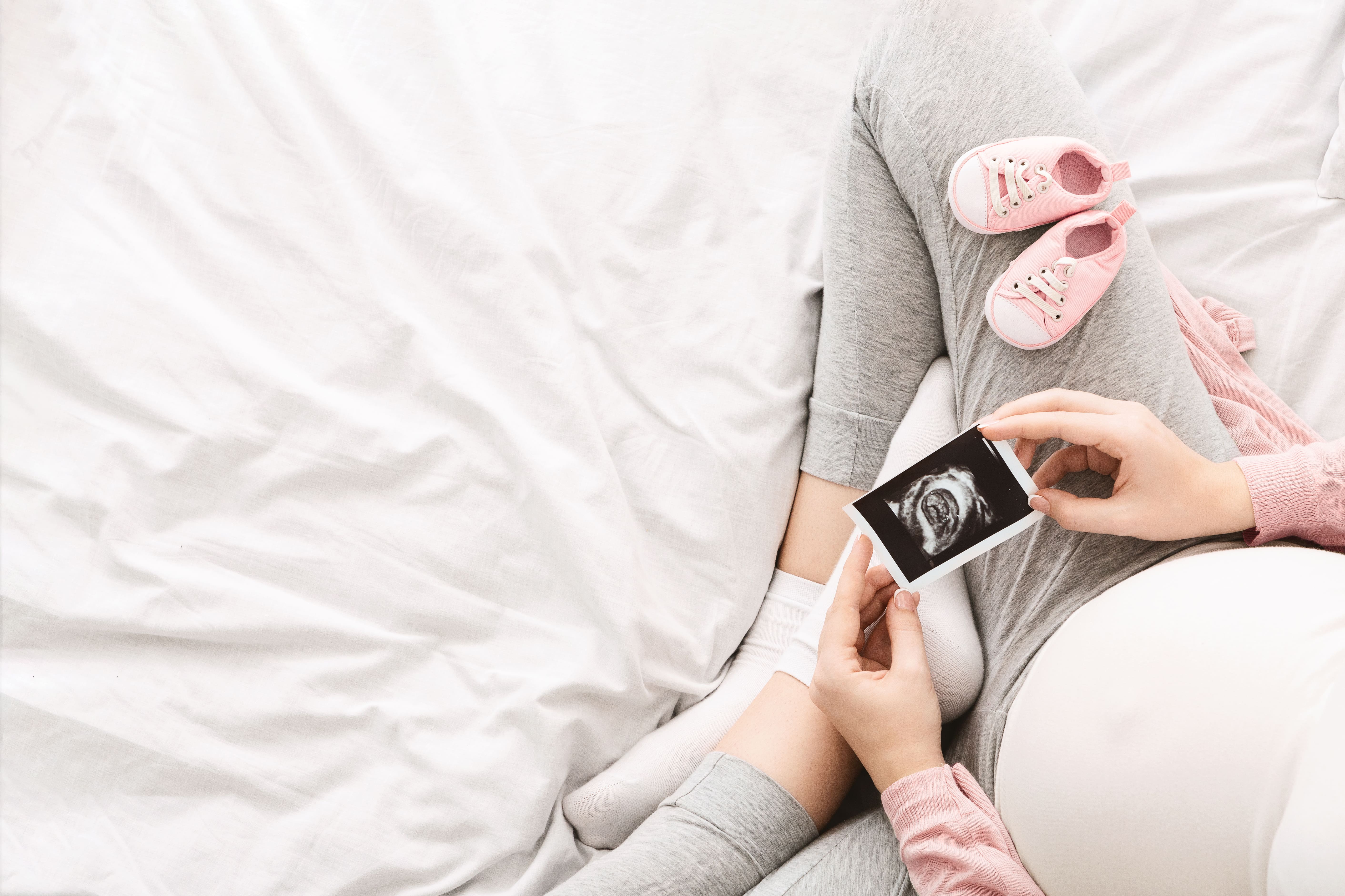 pregnant-woman-lounges-bed-morning-gently-holding-ultrasound-picture-her-baby.jpg