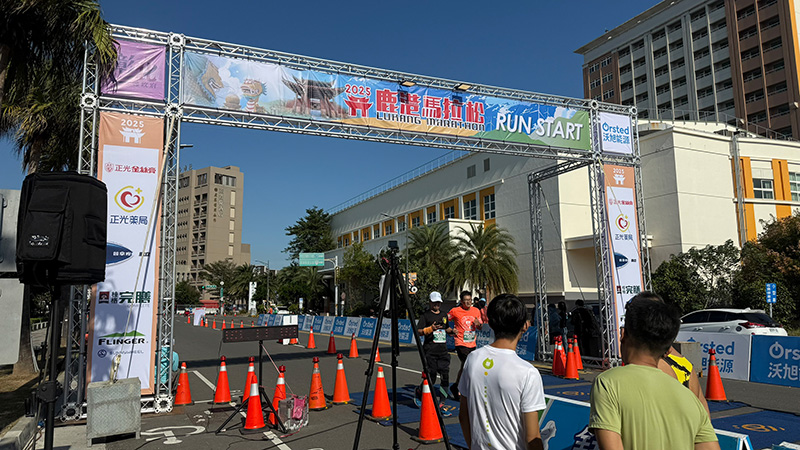2025 鹿港馬拉松終點拱門,跑者陸續通過完賽,拱門兩側柱體可見正光金絲膏之贊助品牌露出。