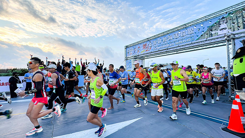 2025 菊島澎湖跨海馬拉松起跑盛況,眾多跑者在晨光中熱情衝出起點拱門,展開跨海挑戰,賽道旁還有熱情的加油團。