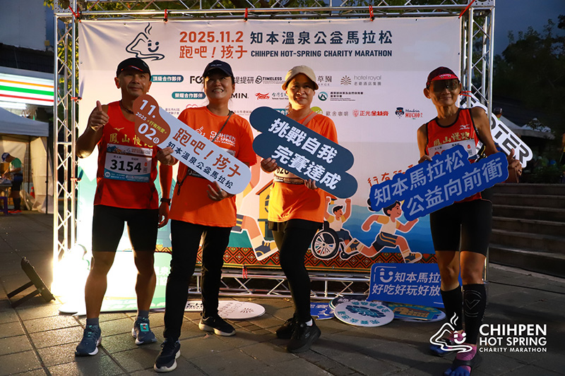 2025 知本溫泉公益馬拉松完賽跑者開心合影,手持『挑戰自我完賽達成』與『公益向前衝』打卡手舉牌,在活動背板前留下熱血回憶,見證正光製藥的陪伴。