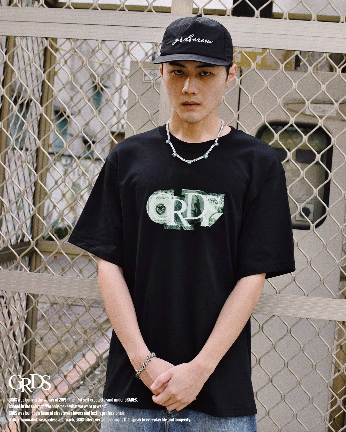 承襲GRDS經典貼紙設計，融入美金元素的視覺衝擊，象徵城市中無可避免的金錢符號。  GRDS 將這股張力轉化為設計語言，將 Logo 疊加鈔票細節，在俐落的黑白底色上展現強烈對比。  黑色沉穩、白色純